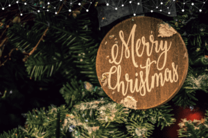 Christmas in Maremma - Merry Christmas written on a wooden decorative ball, in a christmas tree.